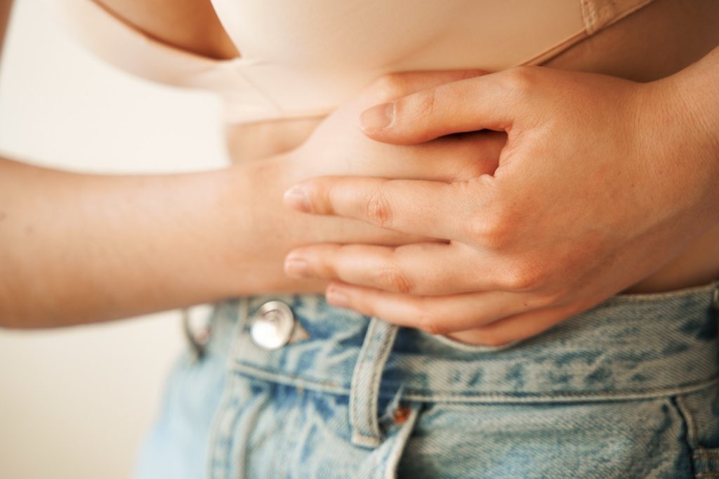 woman holding her abdomen in discomfort due to endometriosis and pelvic pain symptoms.