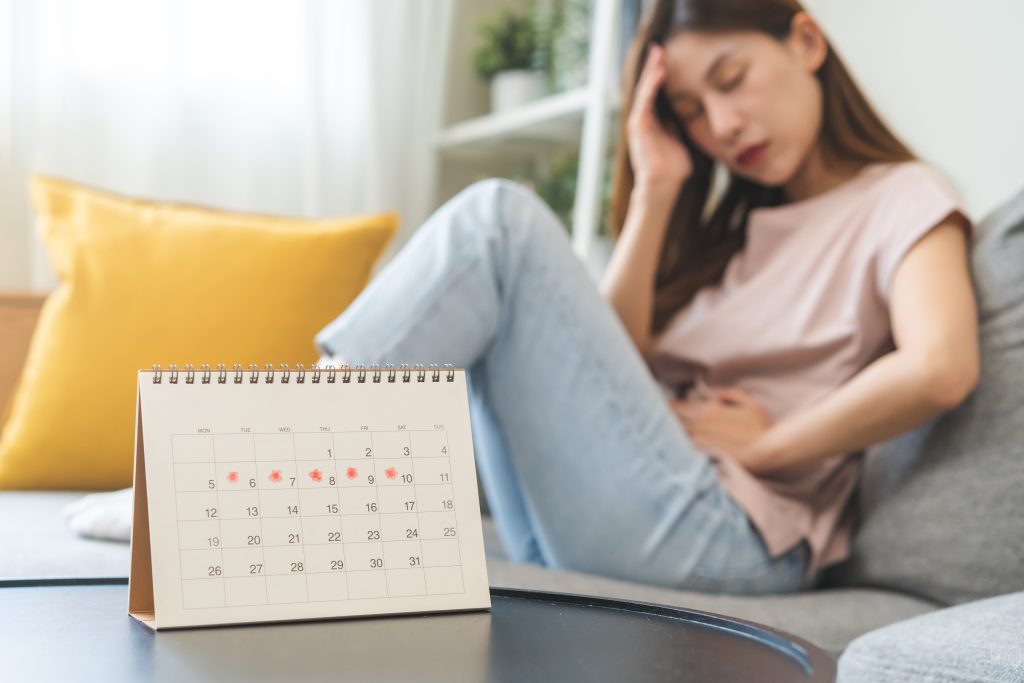 A calendar for tracking heavy periods and irregular menstrual cycles, with a woman resting in the background.