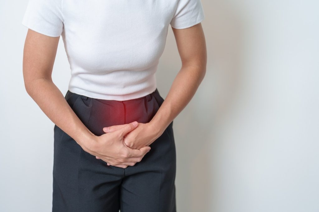 A woman holding her abdomen to express pelvic pain and severe menstrual cramp symptoms.