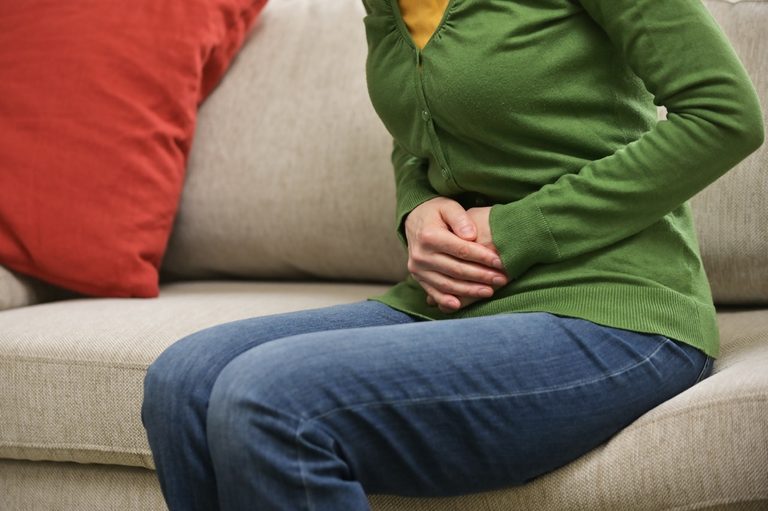 Woman experiencing abdominal pain and cramps from PCOS symptoms.