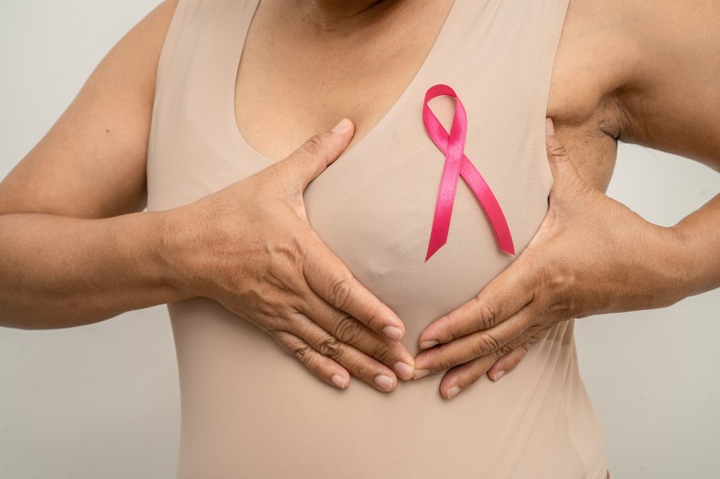 Woman holding a pink breast cancer ribbon.